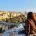 Carlotta seduta su una roccia, mentre guarda il panorama sulla città di Gravina in Puglia e sul suo ponte acquedotto.