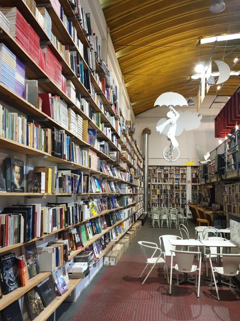 Un angolo della libreria Ler Devagar con alcuni tavolini ed una decorazione che raffigura un ragazzo sospeso in aria da un ombrello