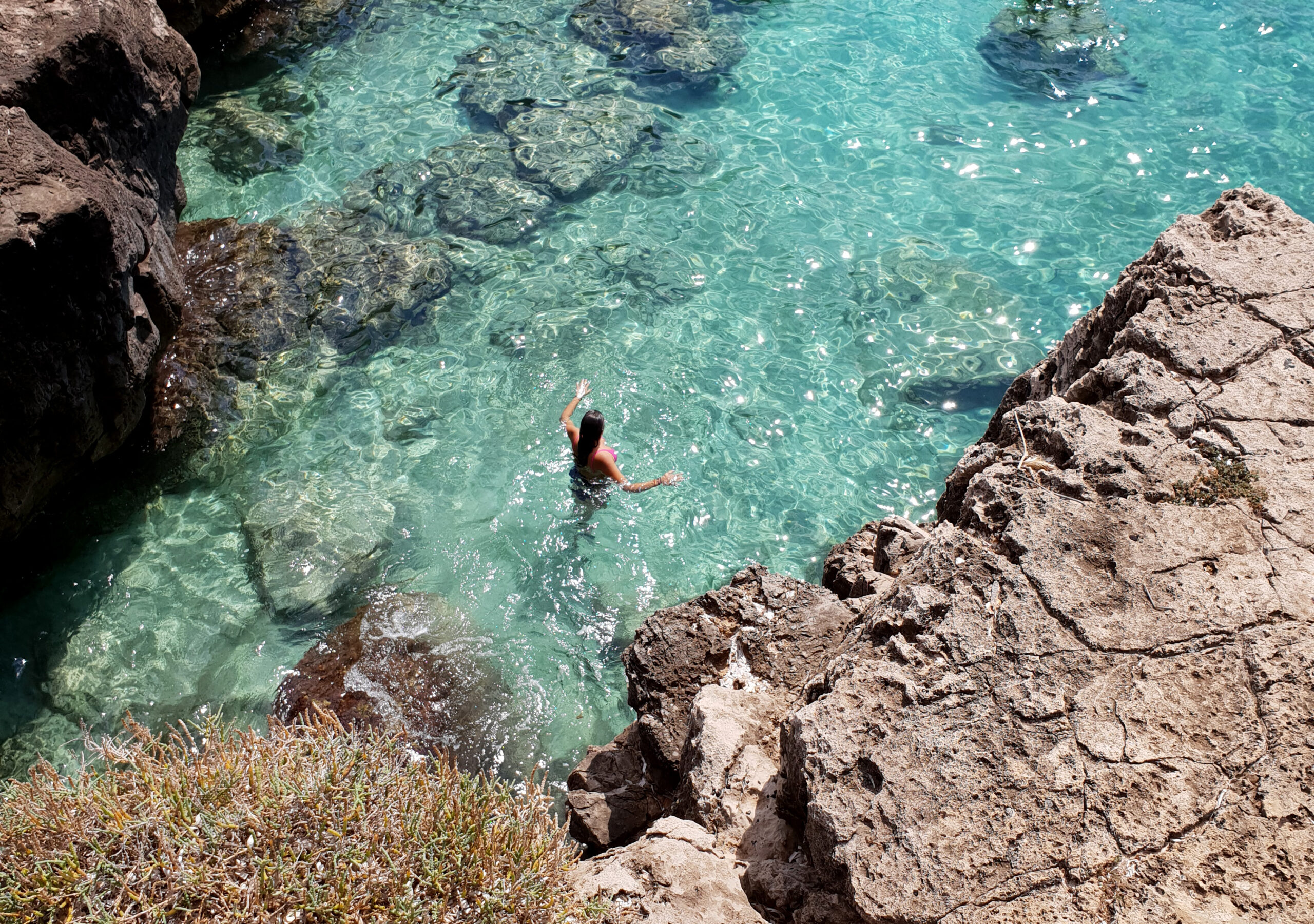 Carlotta immersa in un'acqua azzurra e limpidissima, in una insenatura rocciosa
