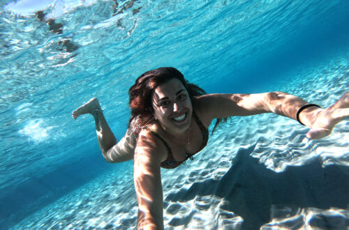 In foto si vede Carlotta che nuota sott'acqua in mare. L'acqua è talmente pulita che sembra di nuotare in una piscina