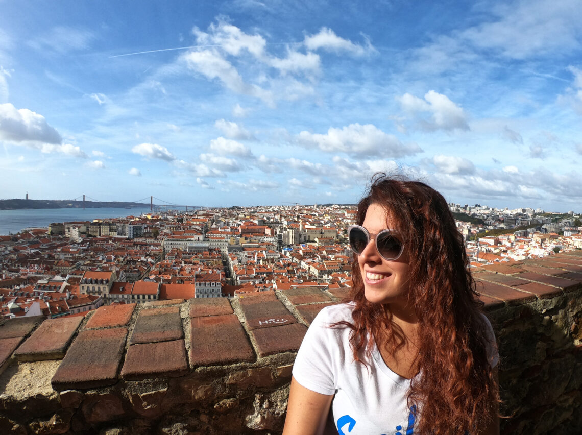 Visitare Lisbona in tre giorni: in foto si vede Carlotta sorridente mentre guarda verso destra, alle sue spalle la città di Lisbona vista dal Castello di San Jorge.
