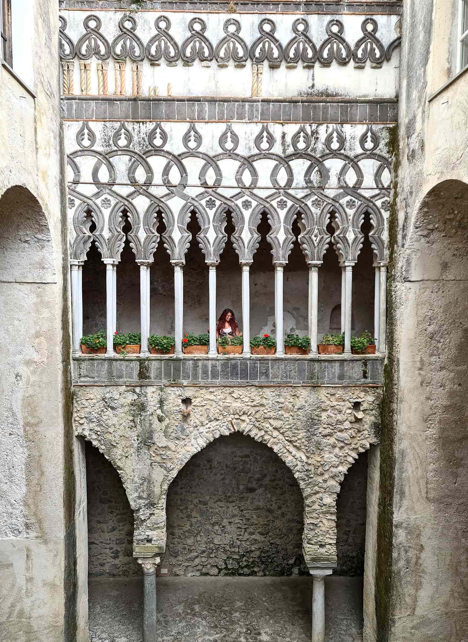 In foto si vede una facciata interna di Villa Rufolo molto elaborata, con tanti archi e colonnine