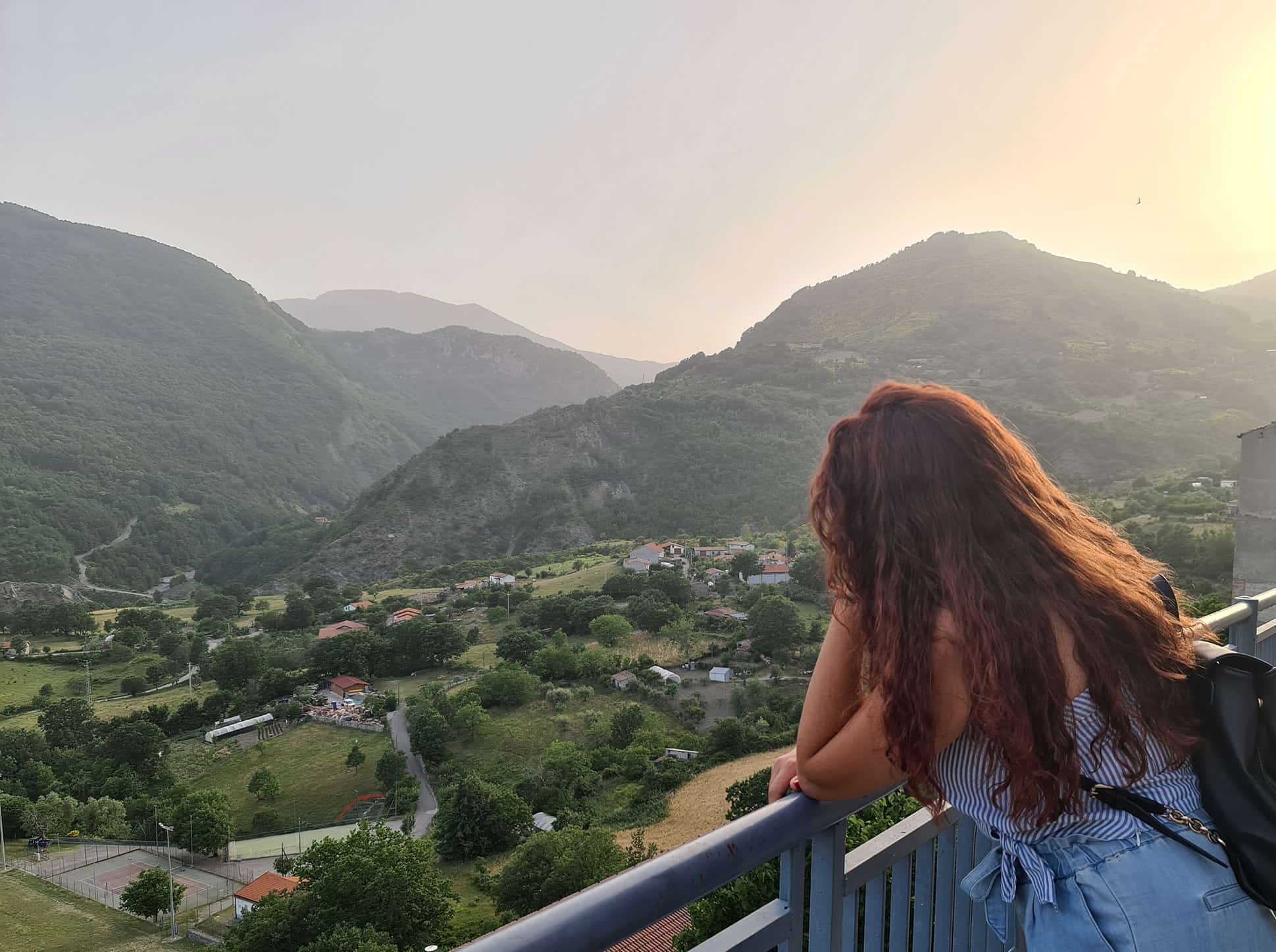 Carlotta appoggiata ad una ringhiera mentre osserva il panorama delle montagne di fronte a Terranova di Pollino