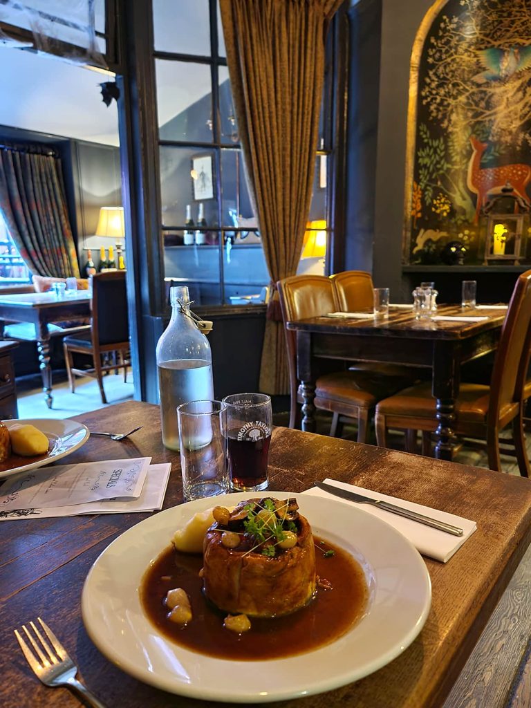 Nella foto si vede il piatto della pie, una specie di torta salata ripiena di carne, e una parte del locale i cui muri sono colorati e vi sono attaccati dei quadri